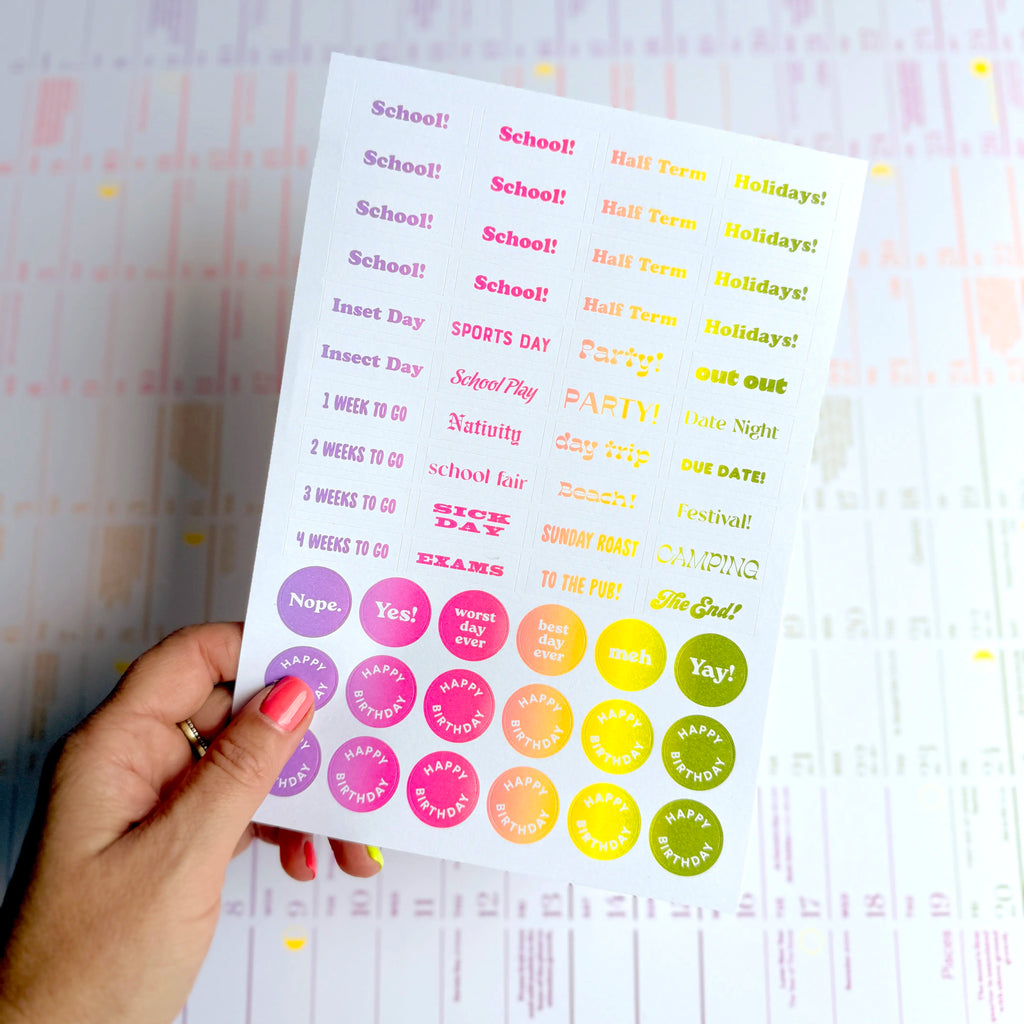 Sheet of colorful stickers to go on a calendar with text and symbols held by a hand. Luckyday Press Classic wall Planner Ladyland press